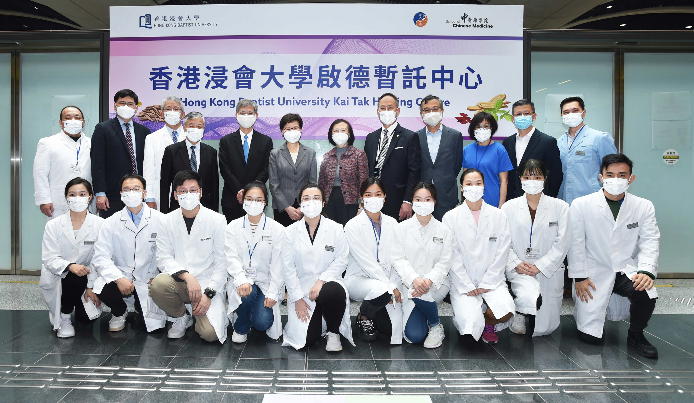 The government officials and organisation representatives visit the Kai Tak Holding Centre operated by HKBU and take photo with the Chinese medicine team of the School of Chinese Medicine at HKBU.