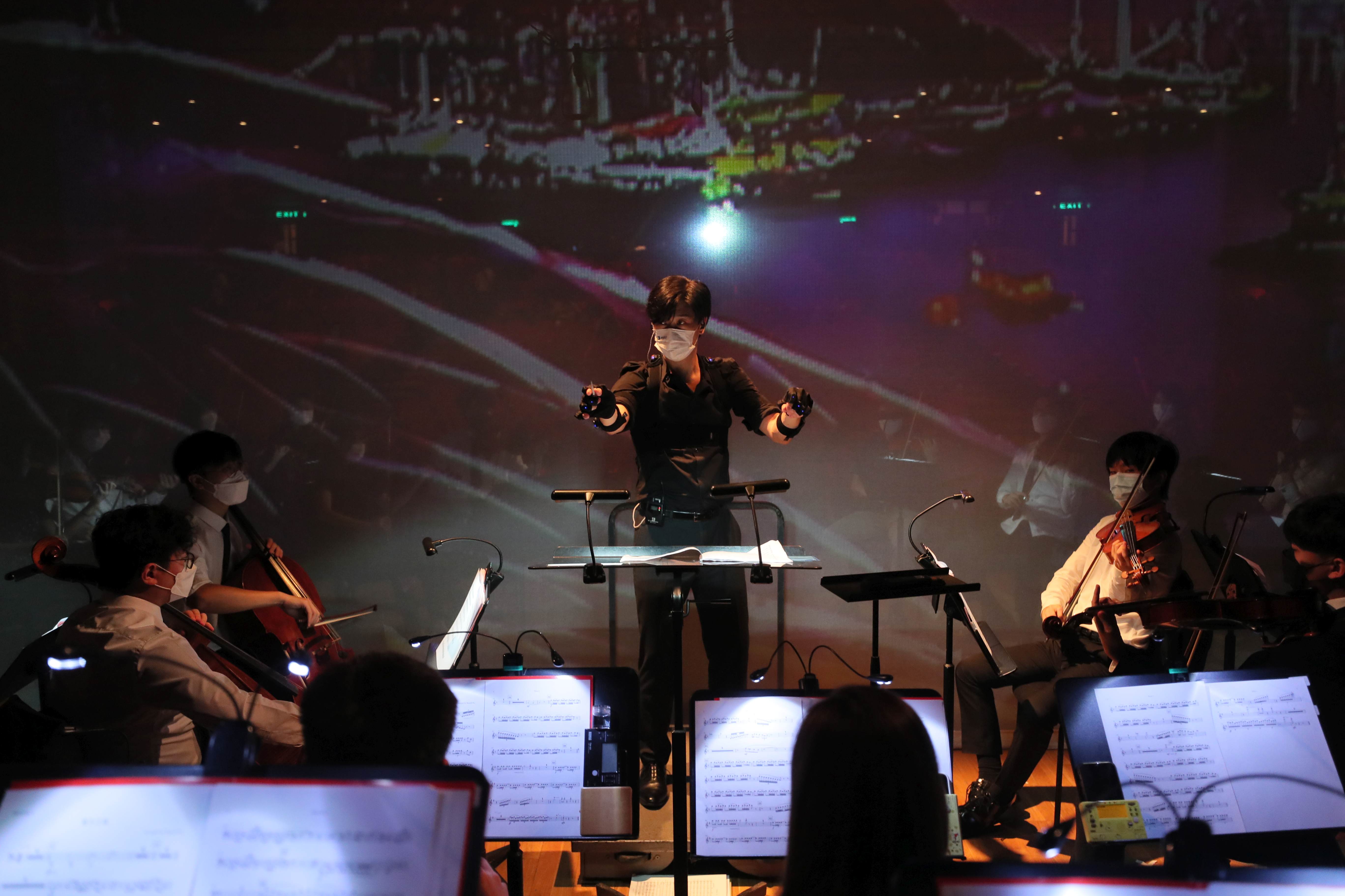 潘明倫教授佩戴傳感器，為交響樂團與AI虛擬合唱團的表演作指揮。